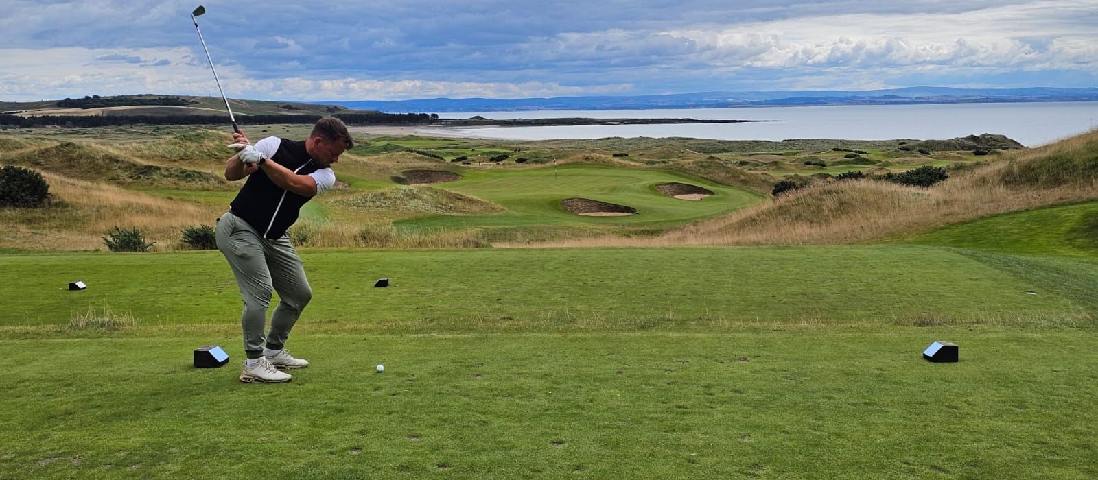 Ash Knight teeing off on a links golf course by the sea