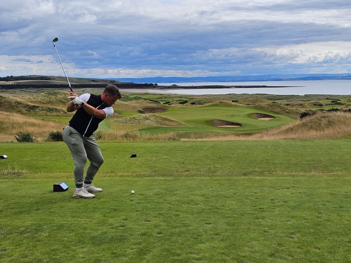 Ash Knight teeing off on a links golf course by the sea